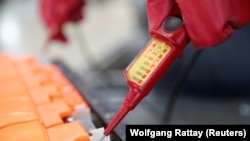 资料照片:在德国回收公司Accurec位于德国克雷费尔德的设施内,一名员工正在拆解一个用过的汽车锂电池。(2017年11月16日)