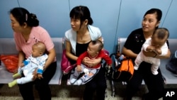 中国妇女抱着孩子等着看医生(美联社2007年9月5日资料照)