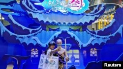 中国网络游戏展览会ChinaJoy2019年8月2日在上海展出期间一名女子与中国一个电子游戏中的一角色扮演者合影。