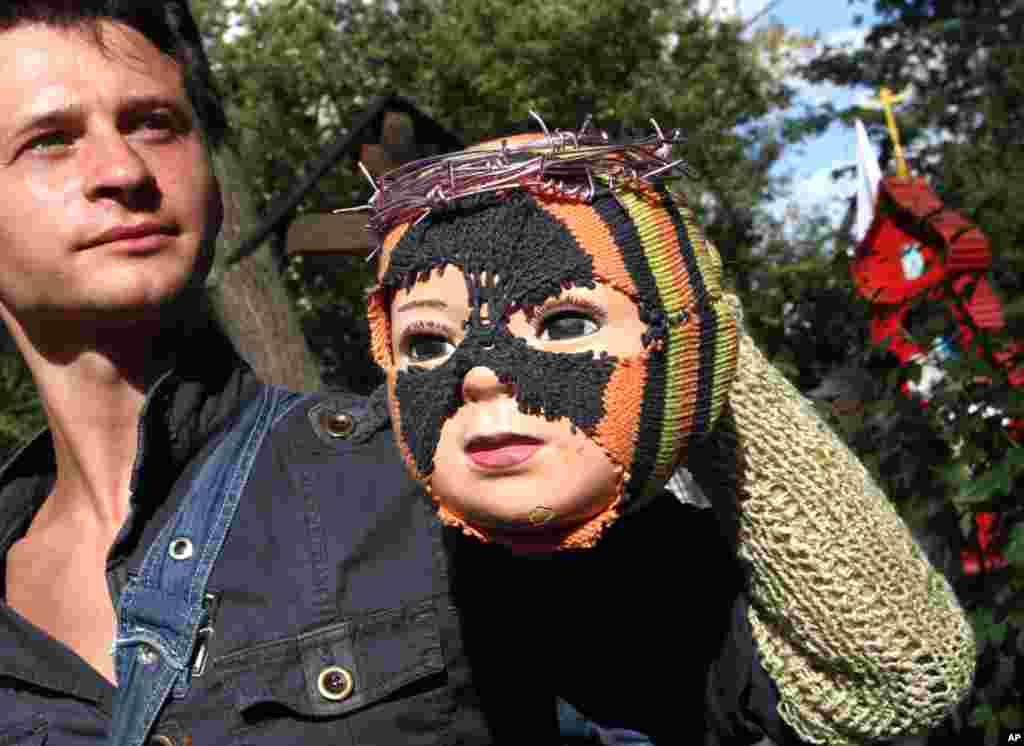 Một thanh niên Nga biểu tình phản đối ở Moscow cầm một con búp bê với trang phục giống như thành viên của ban nhạc