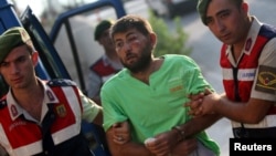 土耳其宪兵队押送在上个月未遂政变中试图捉拿埃尔多安总统的11名突击队员中的一人前往穆拉省一警察总部。(2016年8月1日)