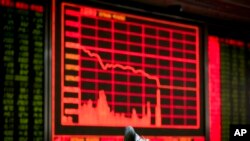 在北京一家证券交易公司,有人观看电子屏幕上的股票信息,屏幕两侧的股价一片惨绿(2016年1月4日)