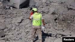 2024年10月16日,在黎巴嫩南部卡纳被以色列袭击破坏的地点,一名救援人员行走在瓦砾上。(路透社照片)