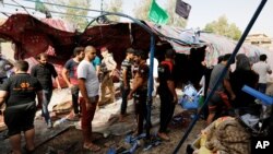 People gather at the site of a suicide bomb attack in al-Shaab district, Baghdad, Iraq, Oct.15, 2016.