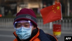 一名戴着口罩和眼罩的男子行走在北京街头。(2020年2月12日)