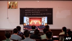 广西柳州一个村庄的村民正在观看在北京人大会堂举行的全国脱贫攻坚总结表彰大会的电视直播。(2021年2月25日)