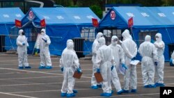 资料照:身穿大白防护服的人负责将来自武汉的人周转到北京某处隔离地点。(2020年4月15日)