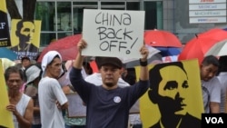 马尼拉艺术家和历史学者卡洛斯•塞尔德兰举着手写的标语牌,参加在中国驻马尼拉领事馆前的抗议活动。(2014年6月12日)