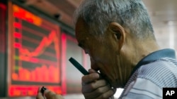 一中国股民7月9日在北京一家交易厅用放大镜查看手机上的股市价格。