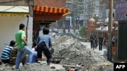 资料照:中国武警守在乌鲁木齐一处维吾尔社区的入口,几名维吾尔人注视着他们。(2019年7月8日)