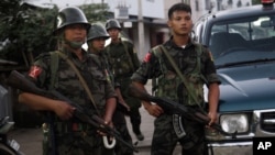 资料照片: 2013年10月28日缅甸克钦独立军(KIA)士兵站在中缅边境城镇拉扎的道路上维持安全。