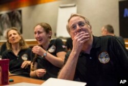 2015年7月14日,“新地平线”科学团队成员收到探测器在驶向距离冥王星最近位置之前发来的最后也是最清晰的照片后欢欣鼓舞。(NASA图片)