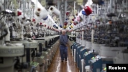 2015年10月22日, 一名工人在阿拉巴马州佩恩堡的 Shankel’s 袜子工厂检查机器(路透社)