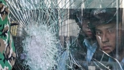 Cảnh sát đứng bên trong tòa nhà chính phủ bị người biểu tình đập cửa kính