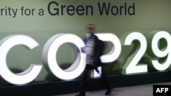 Peserta konferensi terlihat berjalan melewati logo COP29 dalam Konferensi Perubahan Iklim PBB yang berlangsung di Baku, Azerbaijan, pada 21 November 2024. (Foto: AFP)