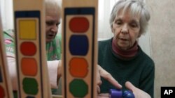 Nhân viên trong khu nhà của người cao tuổi chăm sóc cho một bệnh nhân bị suy giảm trí nhớ (phải)