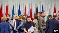 2024年6月16日,乌克兰总统弗拉基米尔·泽连斯基(中)在卢塞恩附近的卢塞恩附近的布尔根施托克胜地出席乌克兰和平峰会全体会议时查看文件。