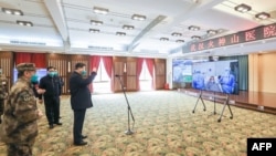 戴着口罩的中国国家主席习近平视察火神山医院时通过视频向新冠病毒感染者和医护人员招手。（2020年3月10日）