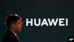 资料照片:2019年1月9日,在北京举行的华为新产品发布会上,一名保安站在华为公司标志旁。中国外交部于2019年1月11日星期五晚间表示,中国正密切关注华为员工王伟晶因涉嫌为中国从事间谍活动而被拘押的事件。