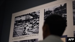 资料照片:一名参观者正在观看中国新闻纪录片摄影记者王小亭(H. S. Wong)拍摄的著名照片《血腥的星期六》(Bloody Saturday)。该照片拍摄于1937年,画面中一名婴儿在上海南火车站的废墟中哭泣,该车站刚刚遭到日军轰炸。这张照片于2014年9月3日在北京的一场关于二战的展览上展出。法国人马库斯·德特雷兹(Marcus Detrez)自称向中国捐赠了一批据称里面装有数百张他祖父在中国抗日战争期间拍摄的照片。(摄影:GREG BAKER / AFP)