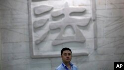 一名男子走过中国一家法院刻有“法”字的墙壁。(资料照片)