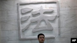 一名男子走过中国一家法院刻有“法”字的墙壁。(资料照片)