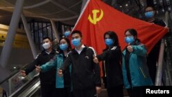 Các nhân viên y tế đến từ những tỉnh khác chụp ảnh lưu niệm trước lá cờ Đảng CSTQ tại ga xe lửa trước khi rời Vũ Hán, tâm dịch COVID-19, ngày 17/3/2020. REUTERS/Stringer