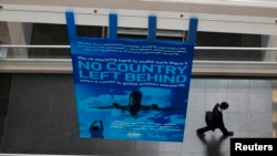 国际民航组织全球会议期间,一位代表走过该组织的标语“不落下一个国家”(2015年2月4日)