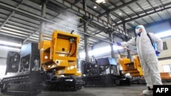 中国江苏省连云港市的一名工人在给工厂的机器喷洒消毒药水为工人节后返工做准备。(2020年2月9日)