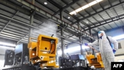 中国江苏省连云港市的一名工人在给工厂的机器喷洒消毒药水为工人节后返工做准备。(2020年2月9日)