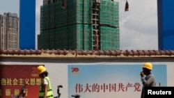 资料照：中国工人从云南省昆明市一处建筑工地旁走过。（2019年9月17日）