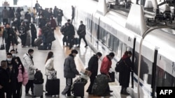 中国湖北汉口火车站的旅客在春节前的春运开始之际登上火车。(2022年1月17日)