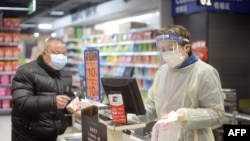 一名戴着口罩,身着防护服的工作人员在武汉一家超市工作。