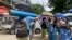 A man carries an oxygen tank while others line up with their oxygen tanks outside an oxygen refill station in Pazundaung township in Yangon, Myanmar, Sunday, July 11, 2021. Myanmar is facing a rapid rise in COVID-19 patients and a shortage of oxygen supplies just as the country i