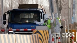 身穿防护服的警察在河北省通往北京的一个道路检查站拦住一辆卡车。(2021年1月12日)