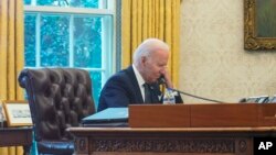 资料照片:在这张通过窗户拍摄的照片中,2021年12月9日,美国总统乔·拜登在华盛顿白宫椭圆形办公室与乌克兰总统弗拉基米尔·泽连斯基通电话。