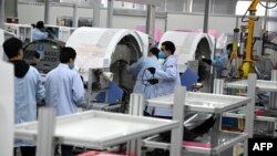 上海生产医疗设备的西门子工厂工人戴着口罩在生产线上工作。(2020年2月24日)