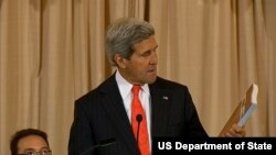 美国国务卿克里在发布会上手持《2014年世界人口走私状况报告》(2014年6月20日, 美国国务院视频截图)