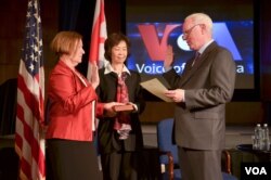 美国之音新台长阿曼达·贝内特(Amanda Bennett,左)一手放在家传的圣经上宣誓就职(2016年4月18日)