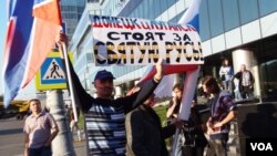 去年秋季在莫斯科爆发了反战和反对俄罗斯干涉乌克兰事务的大游行。一名反对这次游行的人士在游行场外支持手举支持乌克兰东部两个分离地区的旗帜和标语。(美国之音白桦拍摄)