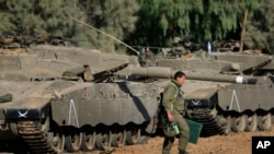 一名以色列士兵走过停在以色列与加沙边界附近的坦克 (资料照片)