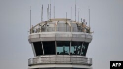Seorang pria memberi isyarat di dalam menara kendali Bandara Nasional Reagan setelah sebuah penerbangan American Airlines jatuh ke sungai setelah bertabrakan dengan helikopter Angkatan Darat AS, dekat Washington, DC, pada 30 Januari 2025. (Foto: Oliver Contreras/AFP)