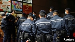 香港警察在逮捕《立场新闻》六名高管后站在该港媒办公楼外。(2021年12月19日)