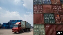 2018年8月7日,中国江苏省张家港港口堆放着集装箱,一辆卡车运输集装箱,在旁边开过。