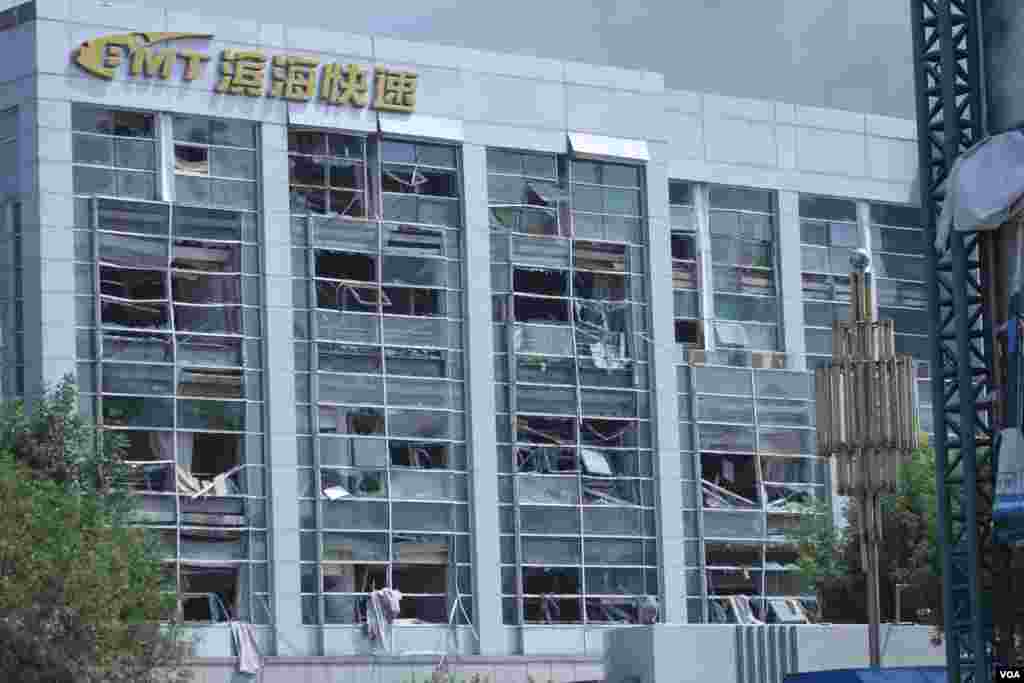 天津爆炸事故现场,核心爆炸区周围多座居民楼窗户被震碎,高速公路桥梁受损,多辆大货车被炸翻,小汽车起火或被砸,多名当地居民仍逗留在事故现场。(美国之音记者东方拍摄)