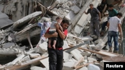 叙利亚阿勒颇由非政府组织控制的街区2016年9月21日遭空袭,一名男子在空袭后抱着一名受伤的儿童。