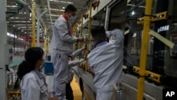 在中国湖北省十堰市的一家工厂,工人为一辆小客车安装窗板。(资料照片:2023年5 月10日)