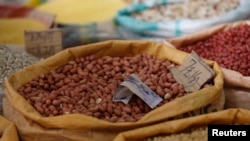 一张五元人民币放在北京一处市场摊位的花生口袋上。(2013年8月9日)