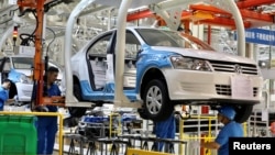 资料照:中国新疆乌鲁木齐市德国大众汽车公司上汽大众工厂的工人正在组装汽车。(2018 年9月4日)