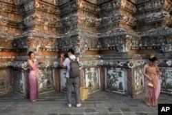 资料照:身着传统泰式服饰的中国游客(左)在曼谷郑王庙或“黎明寺”拍照。(2023年1月12日)